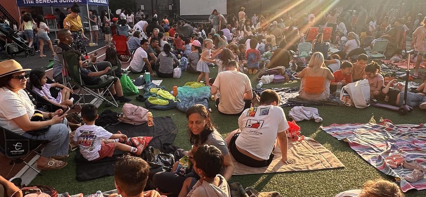 Families and children gathered on blankets at an outdoor movie night